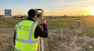 Géomètres du Cabinet Vailles réalisant une implantation topographique sur un chantier de construction au lever du soleil.