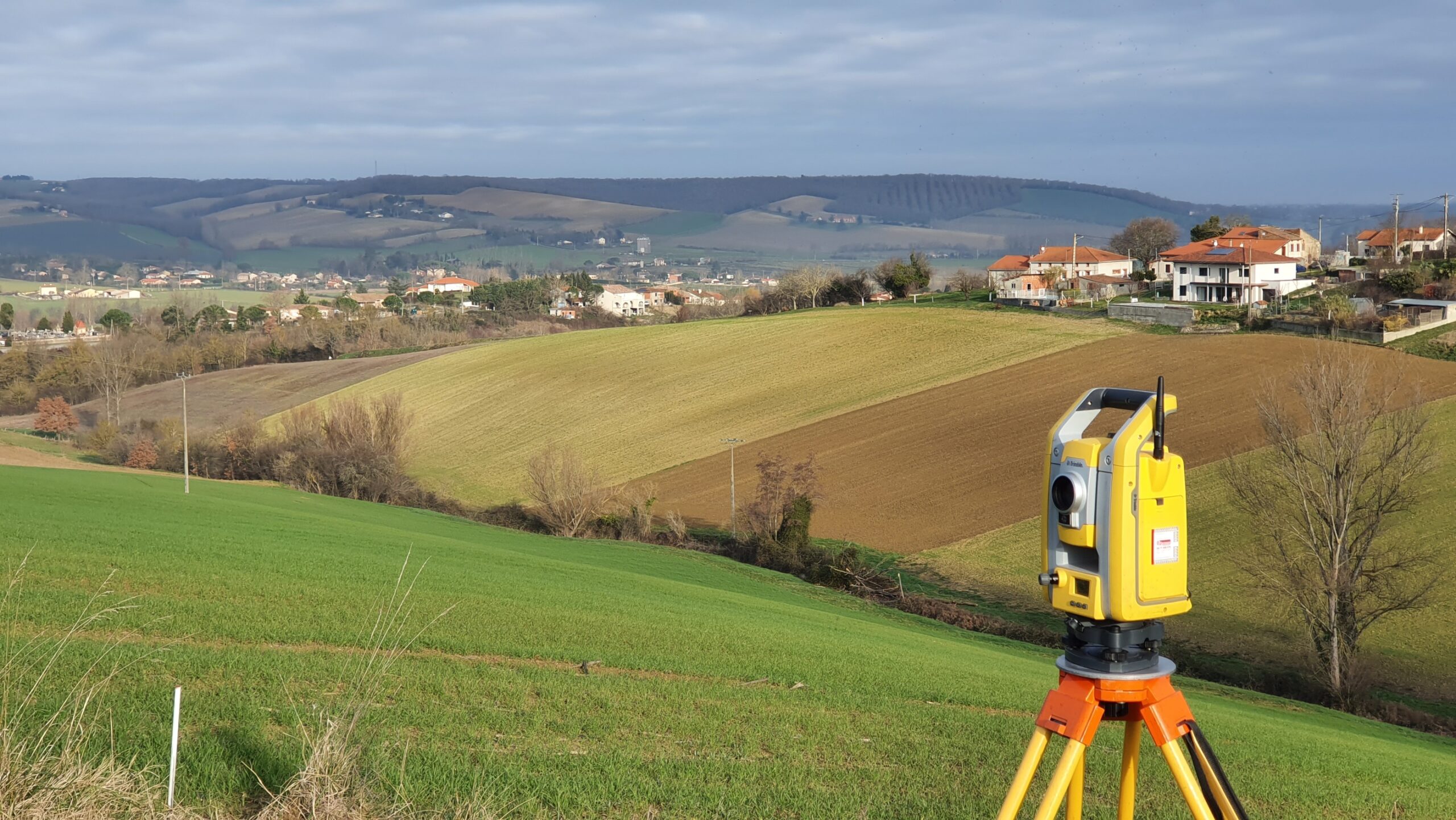 Station totale installée sur un terrain vallonné lors d’un relevé topographique en milieu rural.